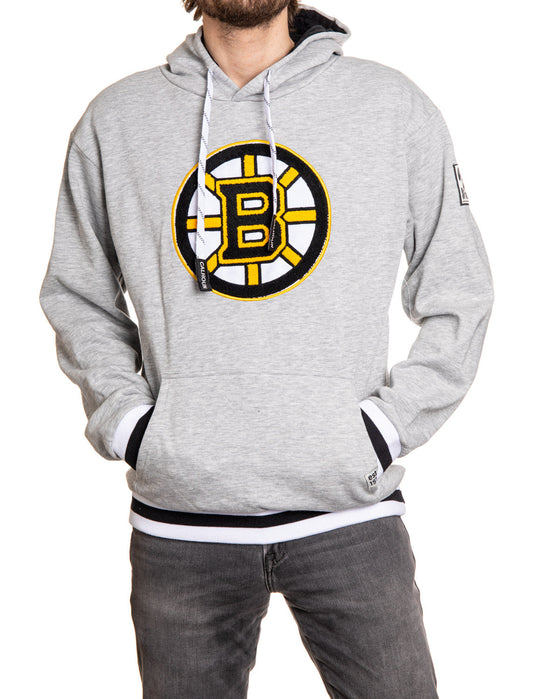 Person wearing a gray hoodie with a sports team logo on a white background