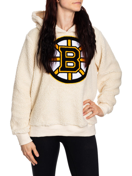 Person wearing a cream-colored hoodie with a sports team logo on a white background