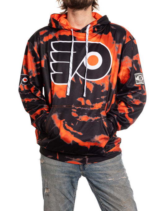 Person wearing a black and orange tie-dye hoodie with a logo, standing against a white background