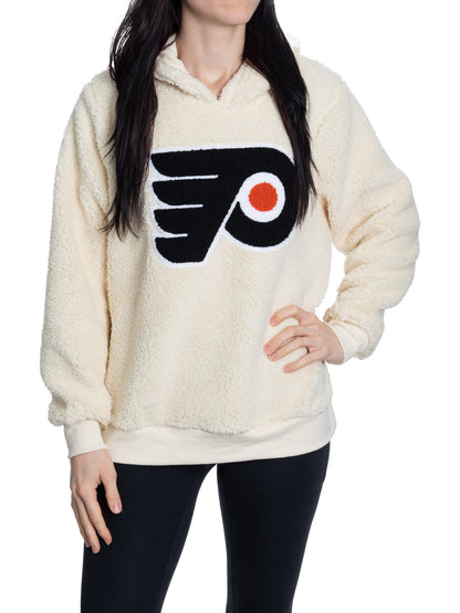 Person wearing a cream sherpa-lined hoodie with a sports team logo on a white background