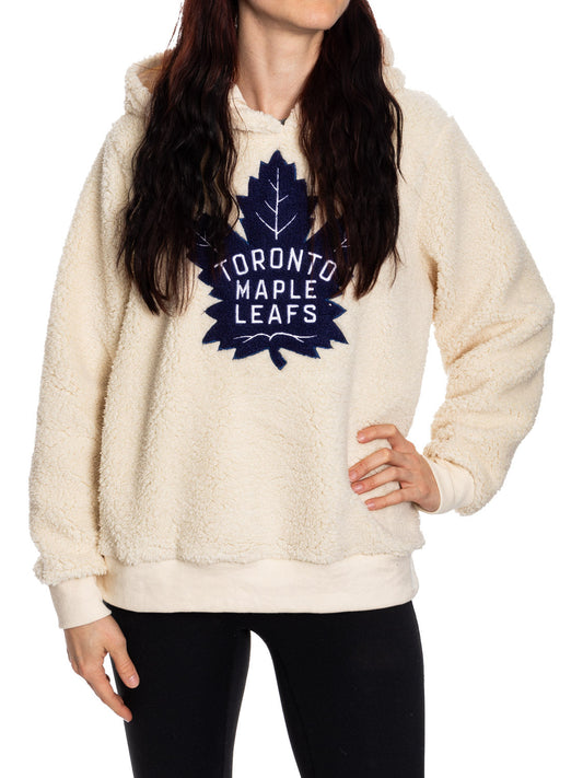 Person wearing a cream Toronto Maple Leafs hoodie on a white background