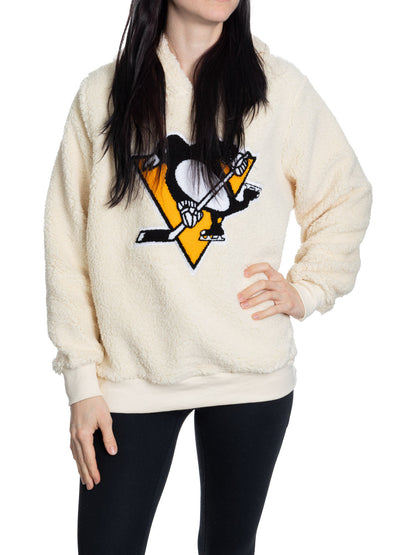 Person wearing a cream-colored fleece pullover with a sports team logo on a white background