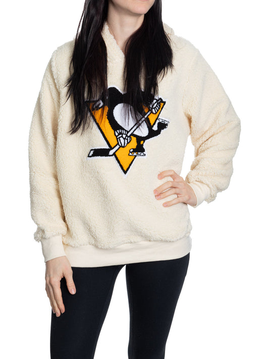 Person wearing a cream-colored fleece pullover with a sports team logo on a white background